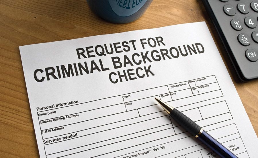 Criminal background check form on a desk with a pen and calculator.